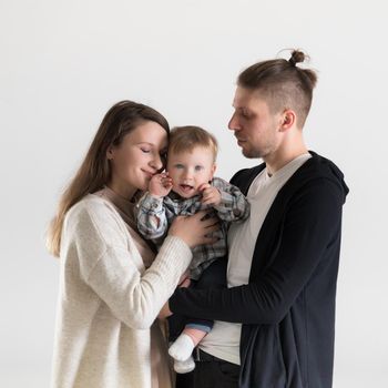 Cute toddler in the arms of his parents surrounded by care and love.