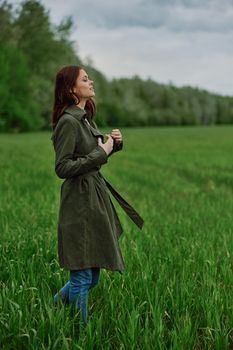 a woman in a long coat stands in a field in cold, windy weather in spring. High quality photo