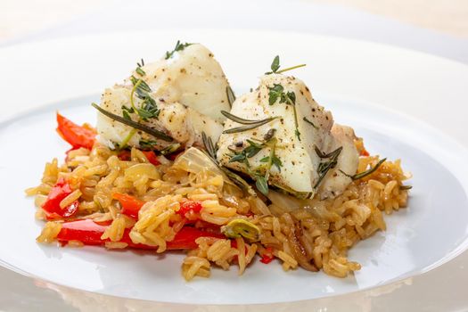 Fish dish - fried cod fillet with boiled white rice and fresh fruit salsa on white table.