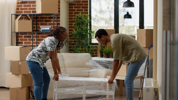 Married life partners decorating rented apartment flat with furniture, preparing living space to move in together and start new beginnings. Unpacking home decor at household property.