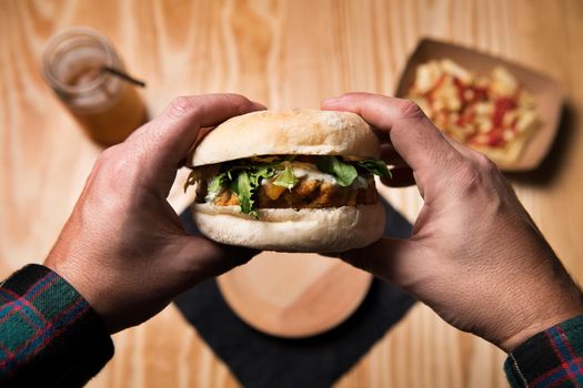 man's hands holding a vegan burger to eat it, healthy food and foodie lifestyle concept, pov image, subjective point of view, selective focus