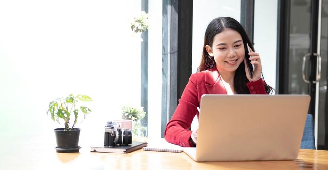 Asian business woman have the joy of talking on the phone, laptop and tablet on the office desk..