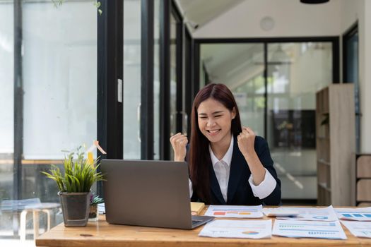 Portrait of happy young business asian woman celebrating success with arms up. positive expression, sucess in business concept.