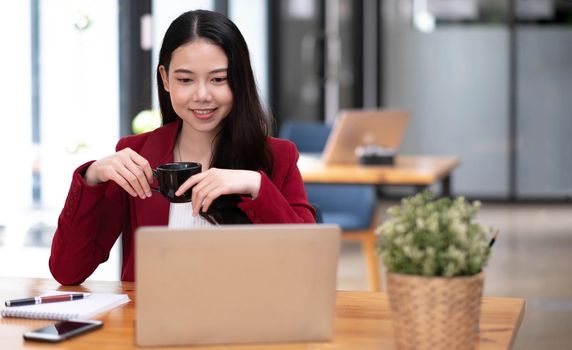 Young asian businesswoman have the pleasure of watching work on their tablet and favorite coffee at the office..