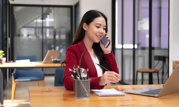 Asian business woman have the joy of talking on the phone, laptop and tablet on the office desk..