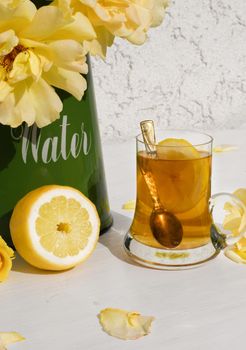 Yellow tea with lemon and a bouquet of yellow roses in a green jug, vintage still life . High quality photo