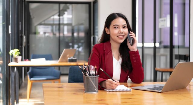 Asian business woman have the joy of talking on the phone, laptop and tablet on the office desk..