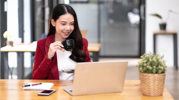 Young asian businesswoman have the pleasure of watching work on their tablet and favorite coffee at the office..