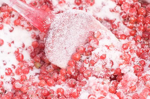 red currants covered with granulated sugar for cooking jam with a spatula in a saucepan. High quality photo