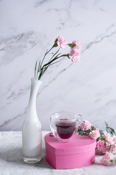 pink carnations in a white vase and coffee cups in a heart-shaped pink box, candy gift for valentine's day, mother's day, birthday. High quality photo