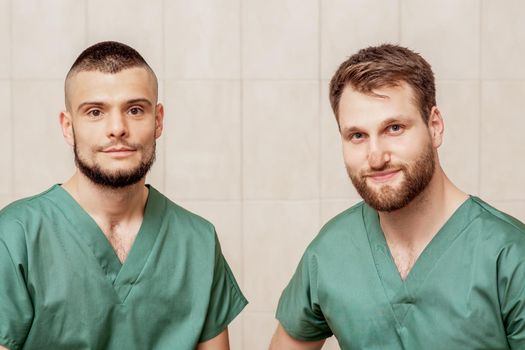 Portrait of two male massage therapists or doctors wearing working clothes at work place.