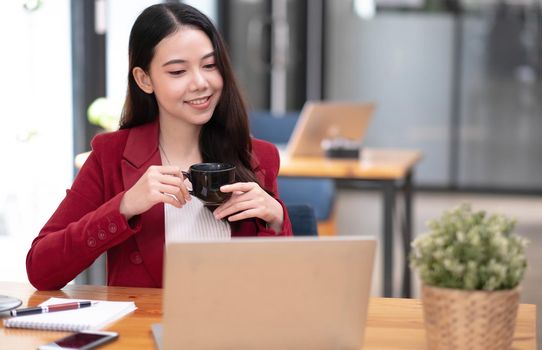 Young asian businesswoman have the pleasure of watching work on their tablet and favorite coffee at the office..