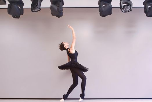 Young ballet dancer black swan practicing before performance in black tutu, classical dance studio, copy space