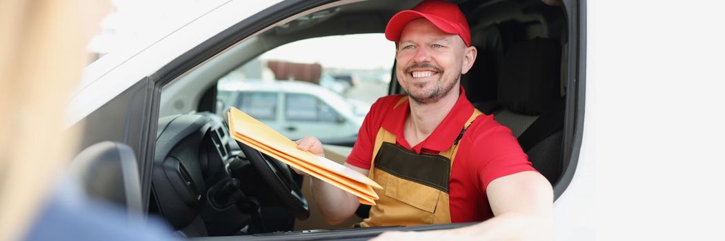 Portrait of joyful worker in uniform give important parcel to owner on address. Courier ask to fill receipt paper. High quality of delivery service concept