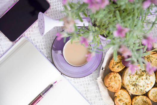 Lavender french breakfast, goat cheese and oven baked baguette, notepad, smartphone, flat lay food, female hand dipping slice of bread in cheese. High quality photo