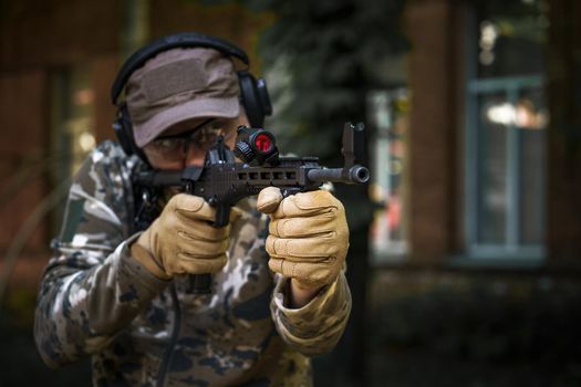 Private military contractor at tactical training course. Shooter with a gun in military uniform. Police training in shooting gallery with weapon. Shotgun weapon action course. Outdoor shooting range.