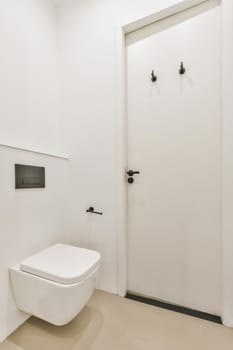 Interior of narrow restroom with sink and wall hung toilet with white walls and checkered floor