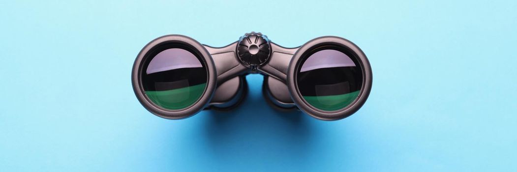 Top view of binoculars equipment placed on blue background with shadow. Necessary tool for explorers and travelers. Search and find, traveling concept