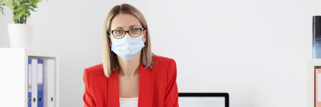 Portrait of cute manager in medical mask posing in office. Preventive measures to protect against virus. Social distancing and quarantine time idea. Coronavirus outbreak concept