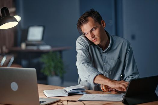 young businessman talking on a smartphone and using a digital tablet. close-up.