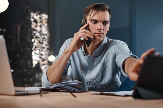 young businessman using a smartphone and a digital tablet in the workplace. close-up.