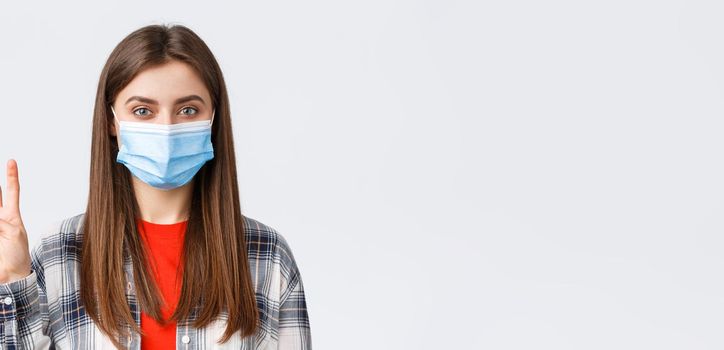 Coronavirus outbreak, leisure on quarantine, social distancing and emotions concept. Cheerful attractive woman in medical mask showing number four, make order, white background.