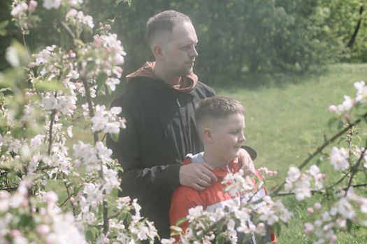 Teenager boy with father together in park in spring.