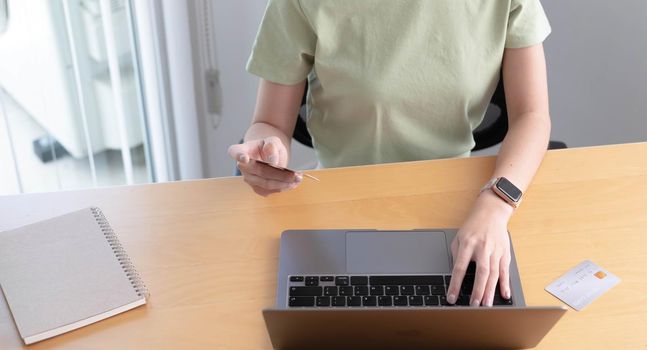 Online shopping. Young woman holding credit card and using laptop at home. African american girl working on computer at cafe. Business, e-commerce, internet banking, finance, freelance concept.