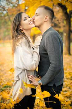 Gentle kiss on a date of a young couple in the autumn park.