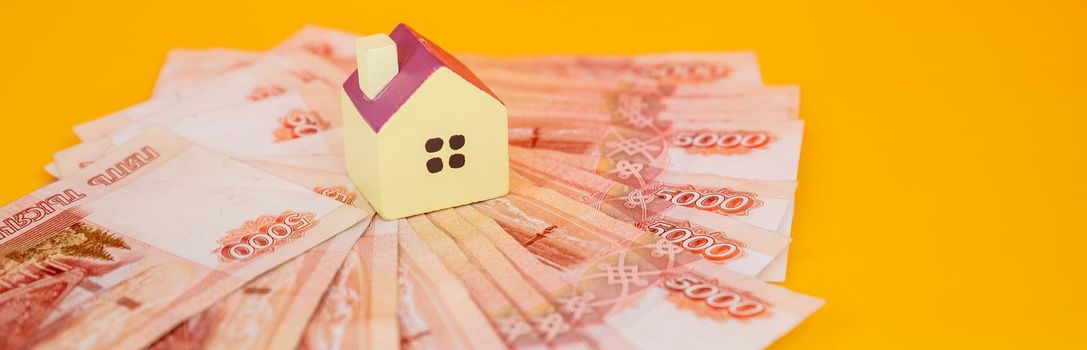 toy house on banknotes, buying your own home, mortgage, symbol of material well being