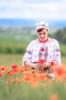 woman in Ukrainian national dress on a flowering poppy field.