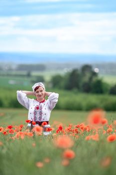 woman in Ukrainian national dress on a flowering poppy field.