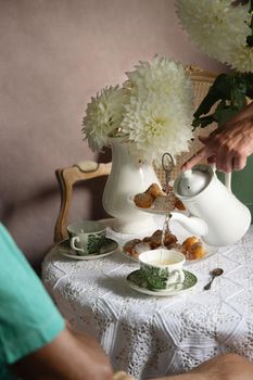 tea break in the English style, still life with flowers and donuts in the morning sun, homemade cakes, married couple drinking tea together at breakfast in english style, beautifully set table