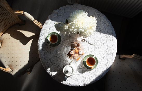 English style tea break, still life with flowers and donuts in the morning sun, homemade cakes, food from above. High quality photo