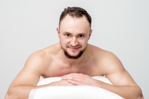 Young caucasian man lying on front on table spa, waiting for beauty treatment and looking at camera