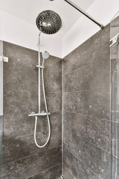 Shower cabinet with black tiled walls and silver appliances