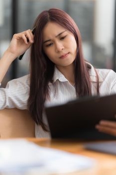 Portrait of Asian business woman worry about marketing plan of this years while looking at data document