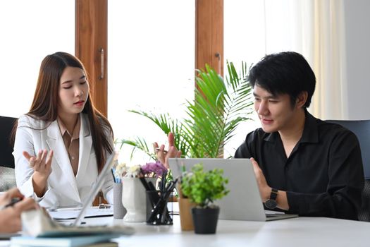 Asian businesswoman sharing ideas, discussing financial report with colleague.