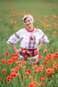 woman in Ukrainian national dress on a flowering poppy field.