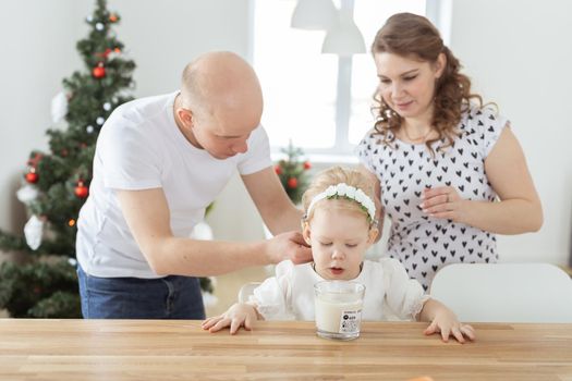 Mother and father helps to put on cochlear implant for their deaf baby daughter in christmas living room. Hearing aid and innovating medical technologies treatment deafness