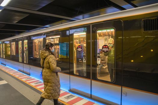 Brussels, Belgium - 01.31.2021 A young woman enters a subway car in a big city on a platform while masked people sit there. High quality photo