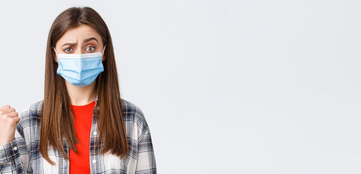 Coronavirus outbreak, leisure on quarantine, social distancing and emotions concept. Skeptical young woman in medical mask express disbelief towards banner to the left, pointing doubtful.