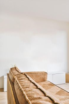 Bright brown colored sofa with pillows in a room with white walls
