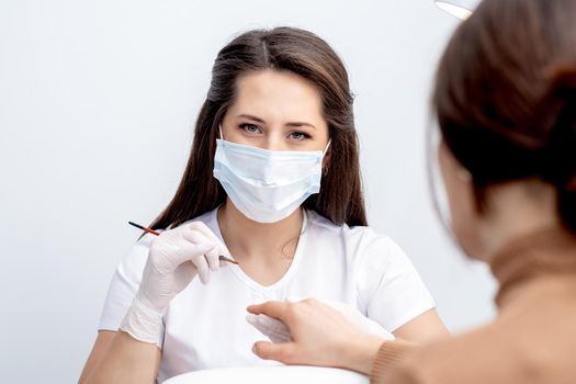 Portrait of manicure master with protective mask working with female customer in beauty salon