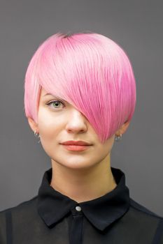 Portrait of a beautiful young caucasian woman with short bright pink hair. Professional hair coloring