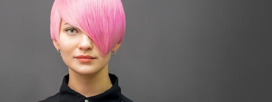 Portrait of a beautiful young caucasian woman with short bright pink hair. Professional hair coloring. Copy space