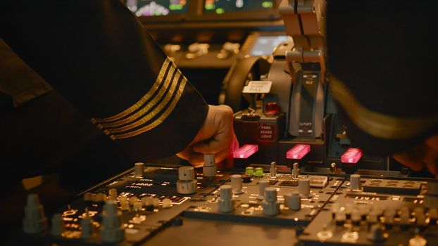 Aircrew captain turning on power buttons to takeoff with airplane, using control panel command in aircraft cockpit. Cabin dashboard with radar compass and engine lever. Close up.