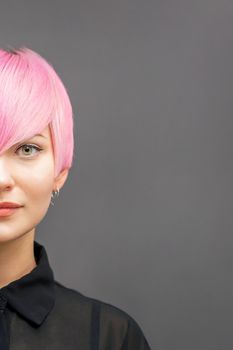 Half face portrait of a beautiful young caucasian woman with short bright pink hairstyle. Professional hair coloring. Copy space