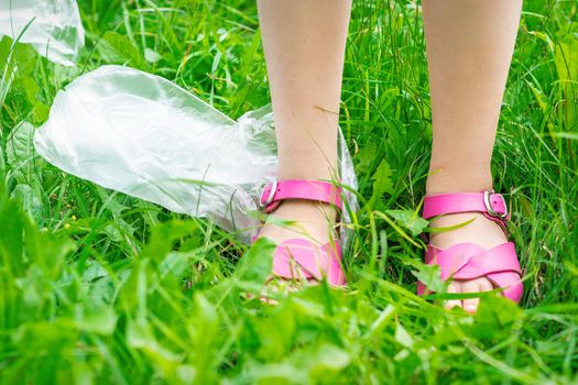 plastic bags trash with children's feet on green grass while cleaning the park from plastic debris