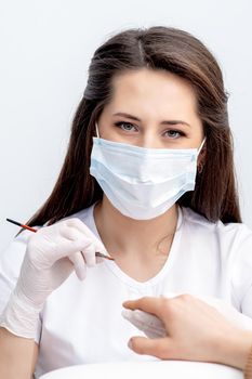 Portrait of manicure master with protective mask working with female customer in beauty salon